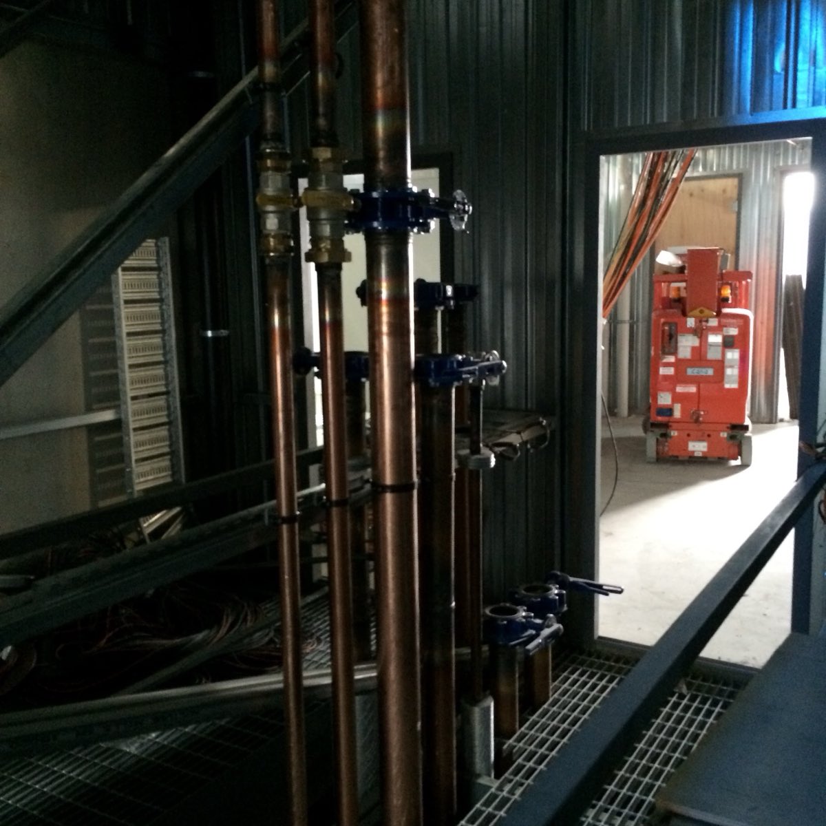 Copper pipework and valves in a plant room, so underexposed that most of the detail is lost to shadow
