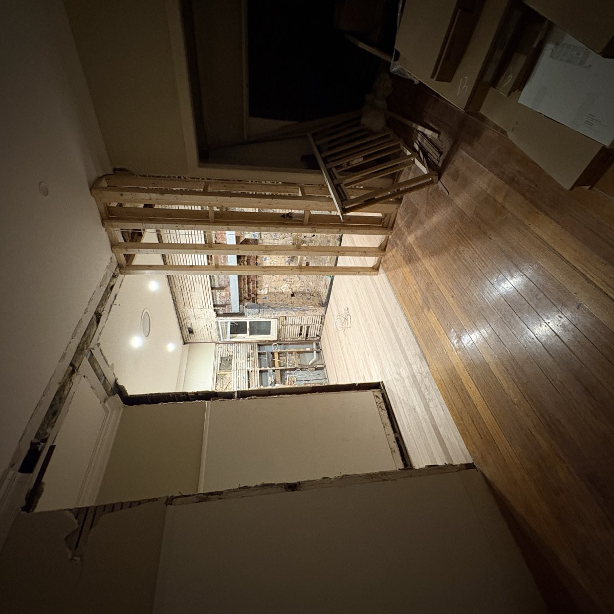 A room mid-renovation photographed in poor light, with the walls and framing muddy and the detail hard to make out