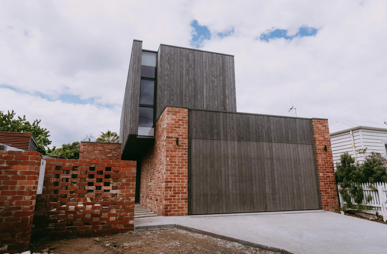 Timber-clad and brick home with a landscaped front garden