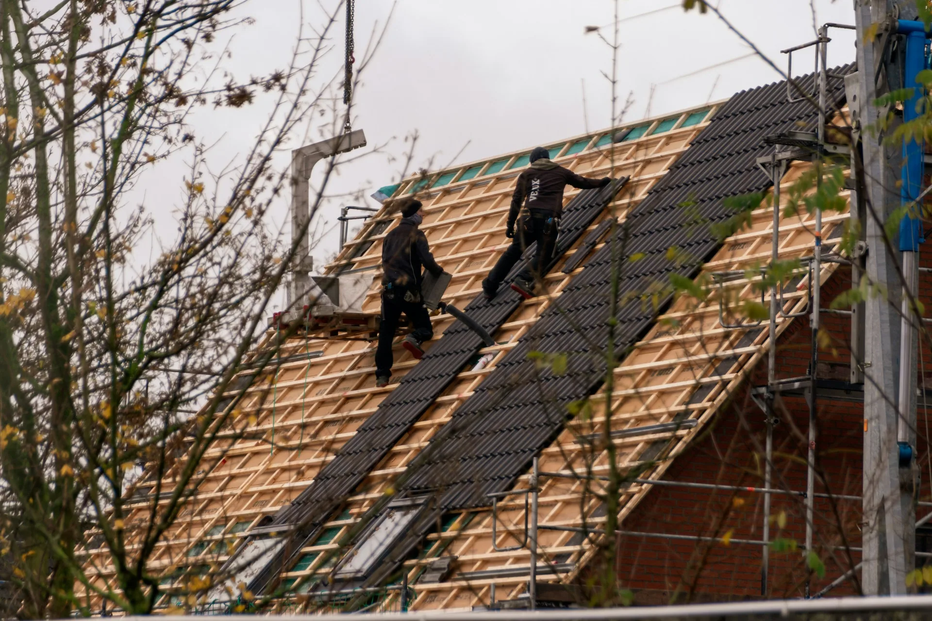 Illustrative photograph of two roofers installing roof tiles